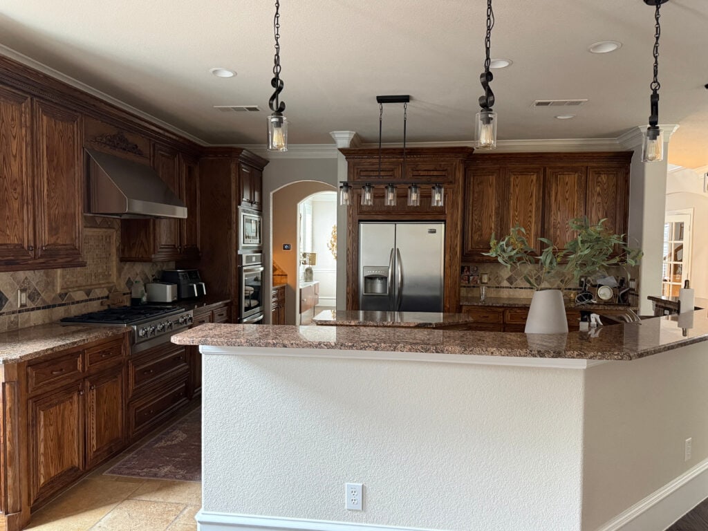 beautiful dark oak wood stained kitchen cabinets, outdated baltic brown look granite countertop, travertine tile flooring and backsplash early 2000s large island with drywall back