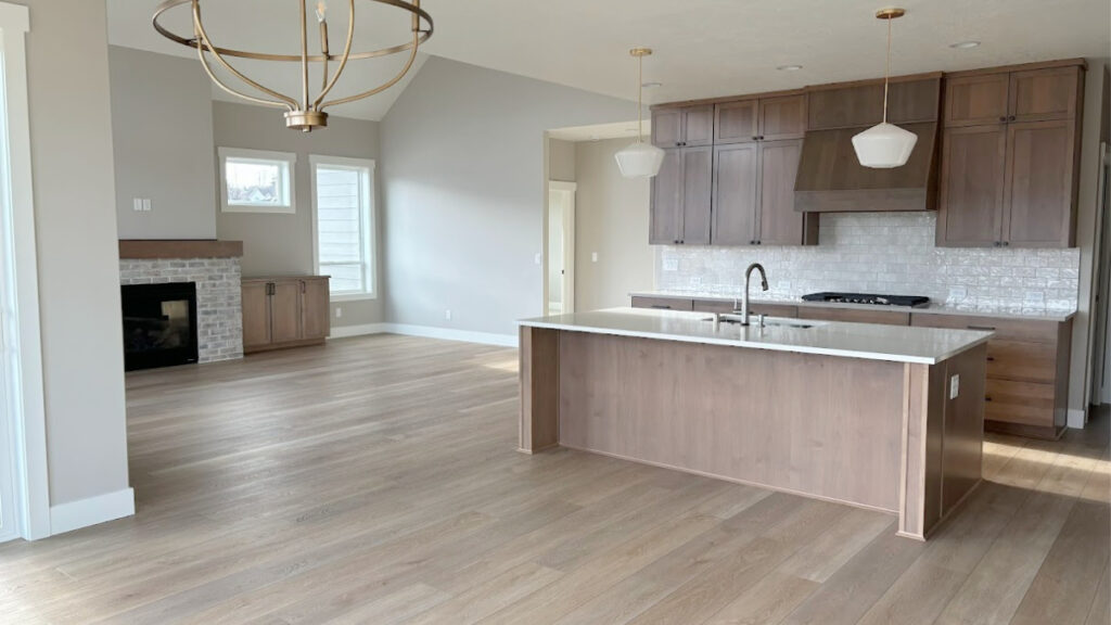 open concept living room, kitchen and dining room. Wood floor, pink undertone wood cabinets, brick fireplace
