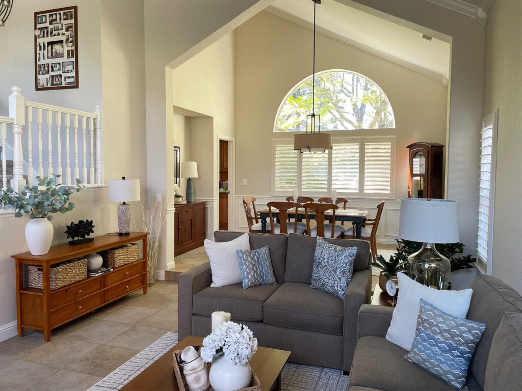 open layout, step-up living room dining room, Sherwin Williams Natural Linen beige walls, brown sofa, vaulted ceiling