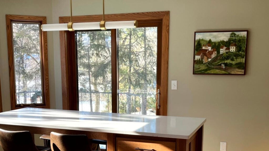 Kitchen with green paint color on walls, red oak cabinets and oak floor, island with white quartz and darker wood trims