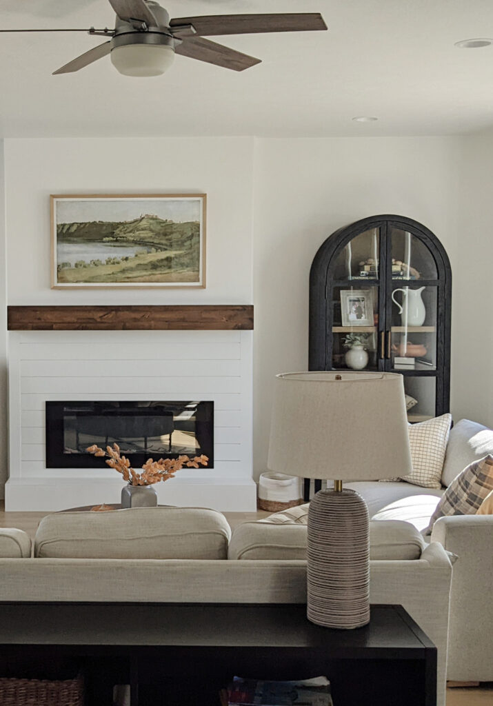 Living room with arched cabinet, off white neutral sofa, Sherwin Williams Pure White walls, shiplap fireplace 8 or 9 foot ceilings, home decor transitional style.
