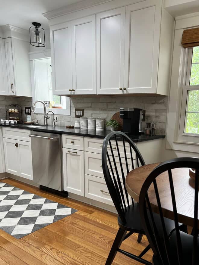 Oak flooring, painted white kitchen cabinets, Sherwin Williams Pure White, black honed granite countertop, tile backsplash, stainless appliances, brass hardware