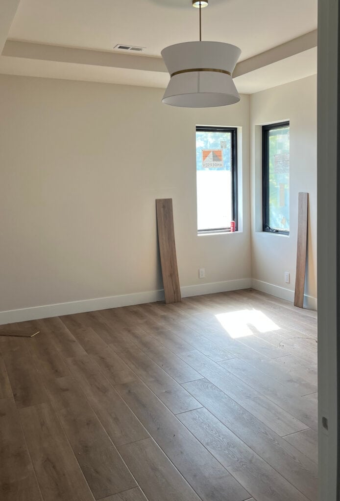 Sherwin Wiliams Aesthetic White, beige paint color with wood floor and low lighting in bedroom