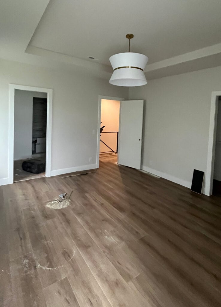 Sherwin Williams Aesthetic White in a bedroom with low muted lighting and wood floor