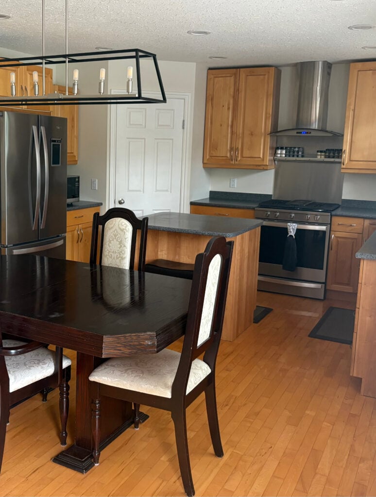 before kitchen with maple or alder wood cabinets and floor, stainless steel. Black laminate countertop
