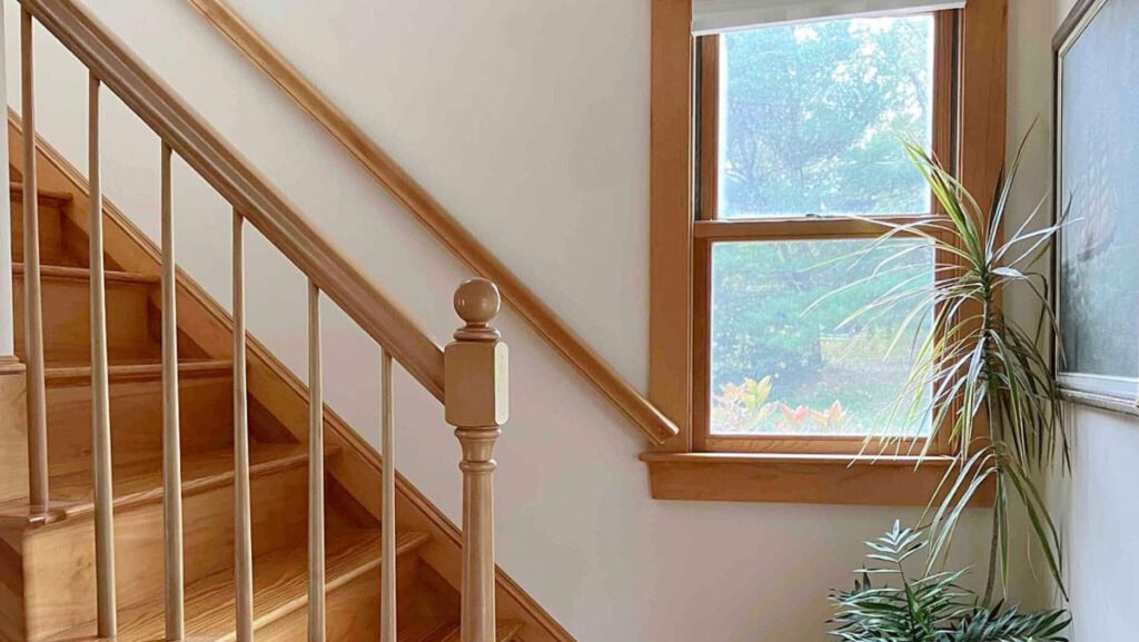 Benjamin Moore Navajo White in a staircase with natural light and pine trims and railings