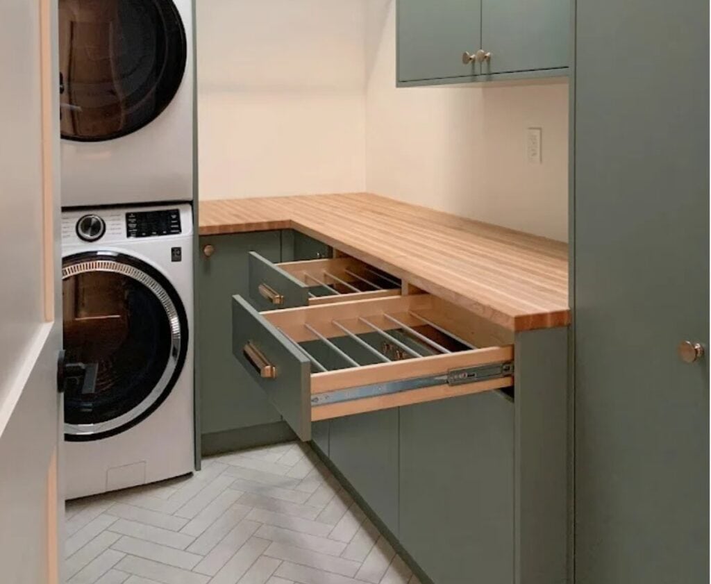 Farrow and Ball Green Smoke, best green paint color on laundry cabinets, wood butcher block countertop, herringbone tile floor, stacked washer dryer