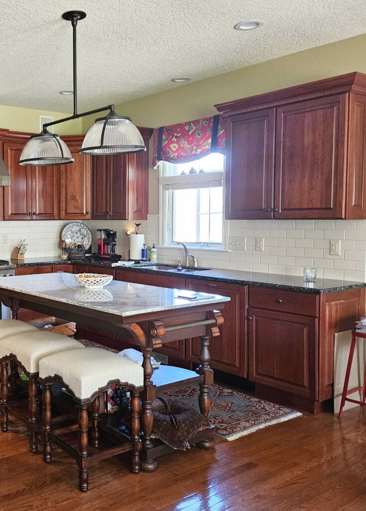 Benjamin Moore Wheeling Neutral iln kitchen, white subway tile, cherry red wood cabinets, oak floor, marble island countertop, stainless steel.
