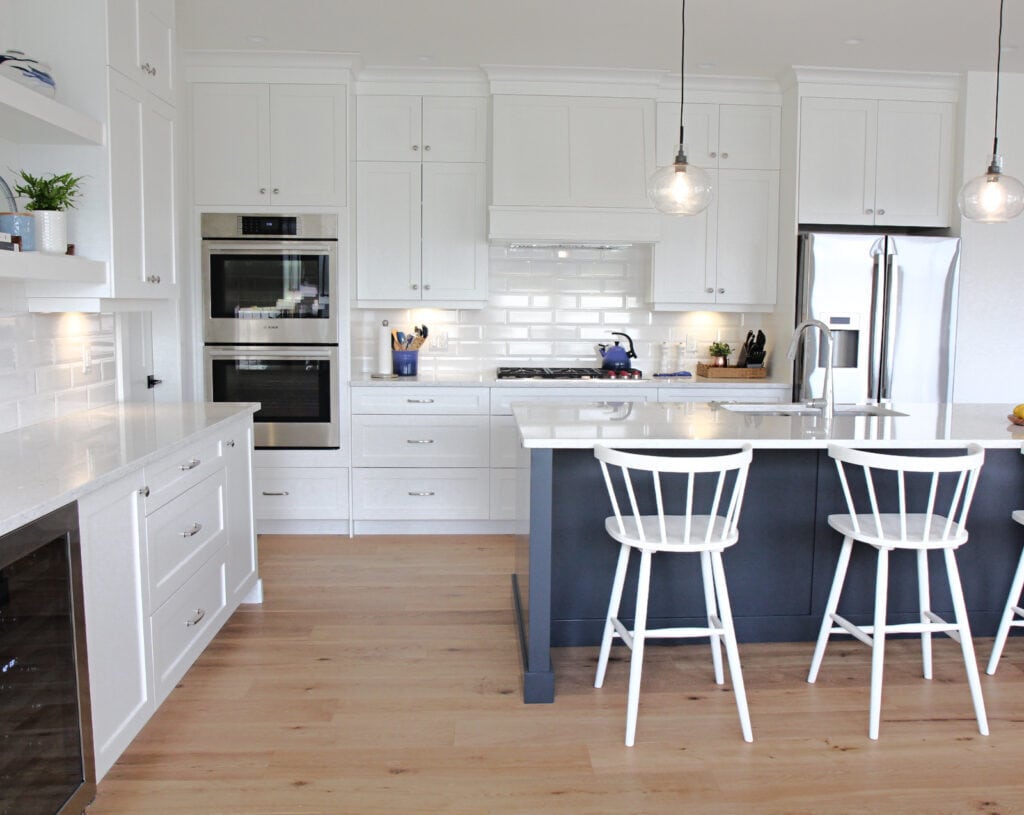 Sherwin Williams Pure White kitchen cabinets, walls, trims, ceiling. Cyberspace navy blue island, white oak floor, white quartz, white subway tile