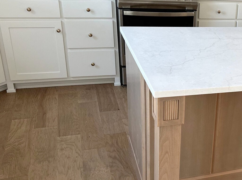 off-white warm gray quartz countertop on island with wood, wood flooring, Sherwin Williams PUre White kitchen cabinets, gold hardware (1)
