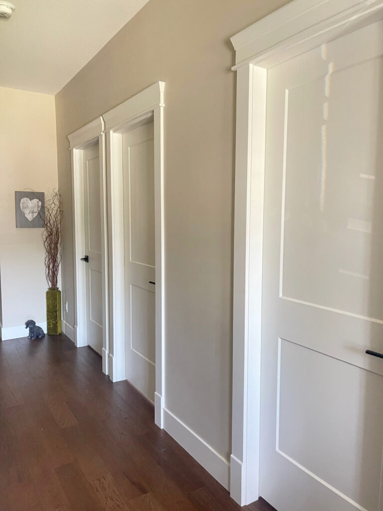 Benjamin Moore Manchester Tan in a hallways with red stained wood flooring and Cloud White trims and doors