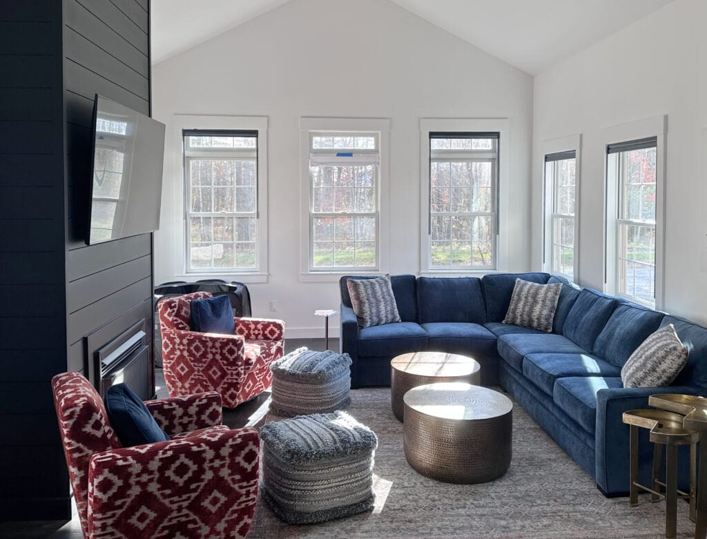 Benjamin Moore Super White with Tricorn Black shiplap painted fireplace in vaulted living room or familyroom, dark navy blue sectional and red accents (3)