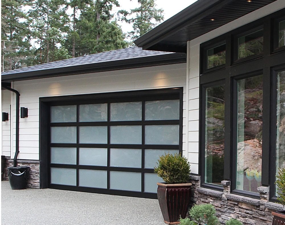 Exterior, modern contemporary home, James Hardie Cobblestone siding, Black windows, dark gray roof, black and glass garage door, black gutters, soffits, and downspouts