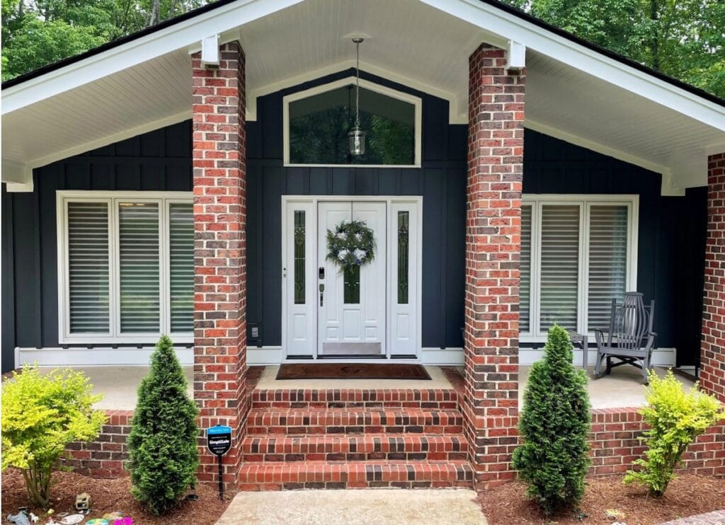 Hardiboard Iron Gray siding, dark gray-blue, red brick exterior, Sherwin Williams Extra White trim and front door, mid-century style subtle