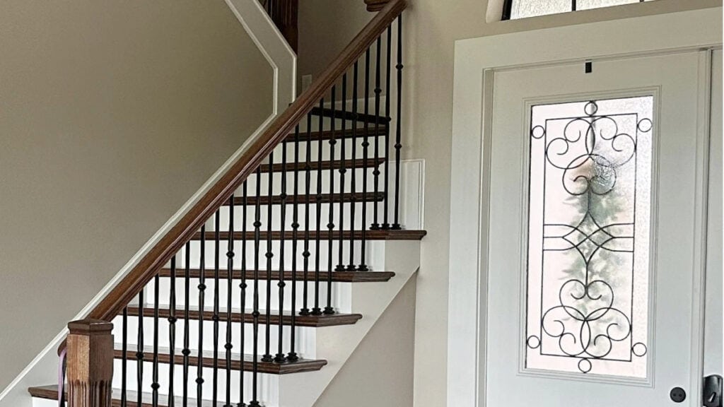 Sherwin Williams ACcessible Beige in entryway on walls, Alabaster trim, wood stair railing and metal spindles, stairs have white risers