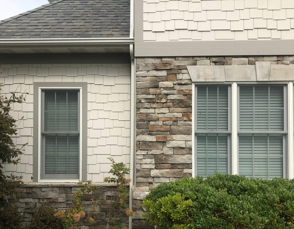 Sherwin Williams AGreeable Gray on painted exterior siding, Acier trim with white windows, gutters match trim color. Stone facade