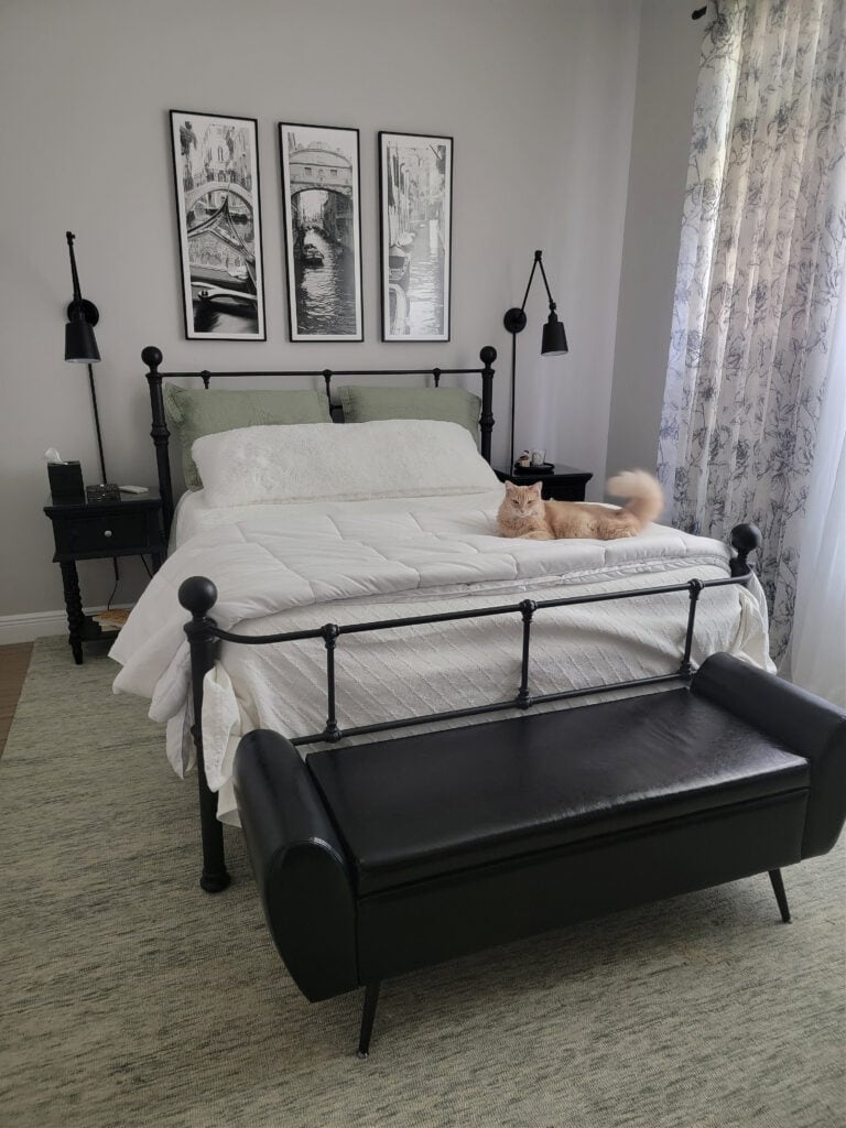 Sherwin Williams On the Rocks, similar to Behr Chic Gray  on walls in bedroom,black metal wrought iron bed frame, bench, linens. Green carpet