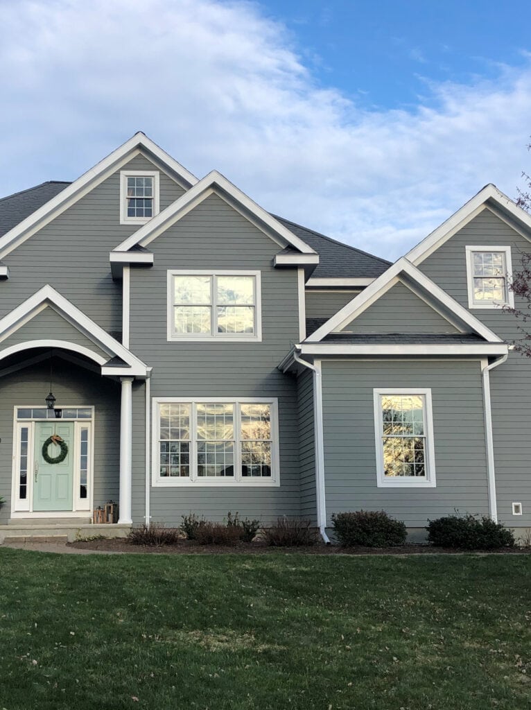 White windows and gutters on exterior painted Sherwin Williams Classic French Gray, Extra White trim, Benjamin Moore Wythe Blue front door