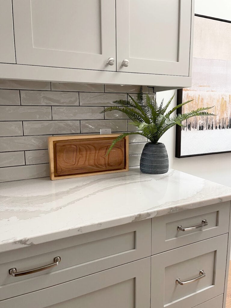 Kitchen cabinets painted BEnjamin Moore REvere Pewter darkened, similar to Mindful Gray. CAmbria Britannica Warm off-white quartz, nickel hardware, gray subway tile backsplash