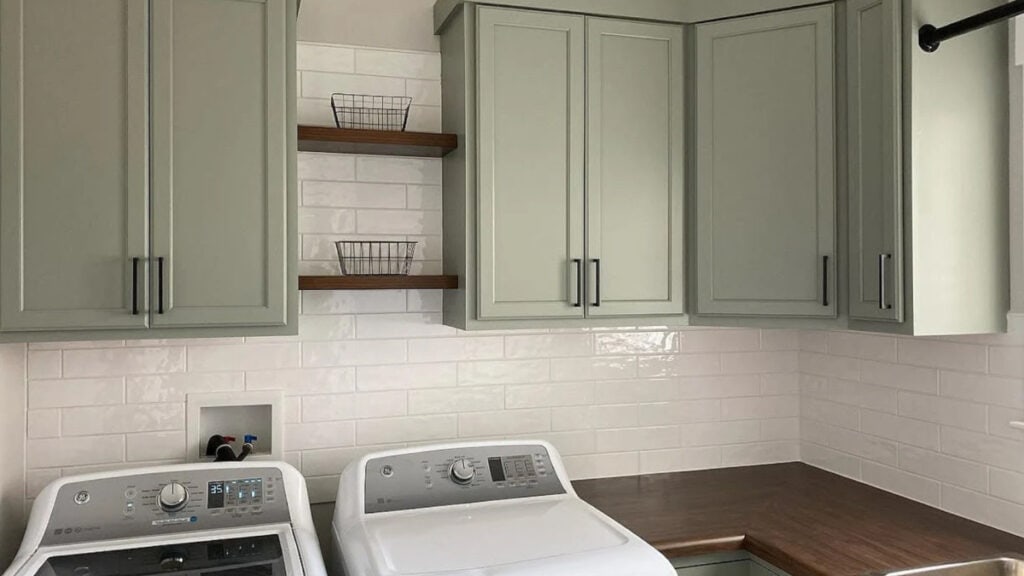 Laundry room with painted Evergreen Fog cabinets, white subway tile backsplash, butcher block wood look laminate countertops with white washer drye