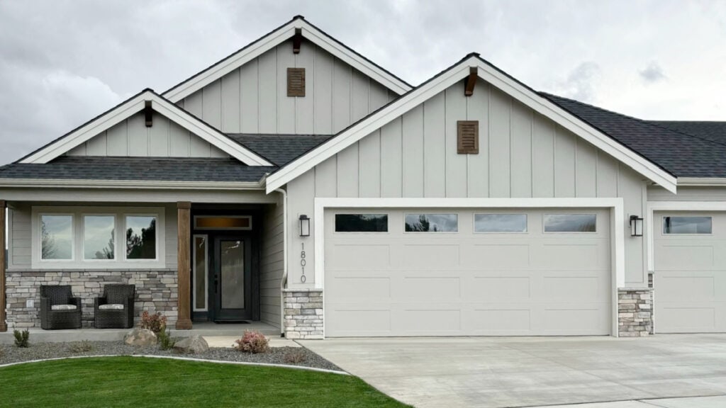 exterior painted sherwin williams agreeable gray with neutral stone, wood beams, white trim and matching garage doors to siding