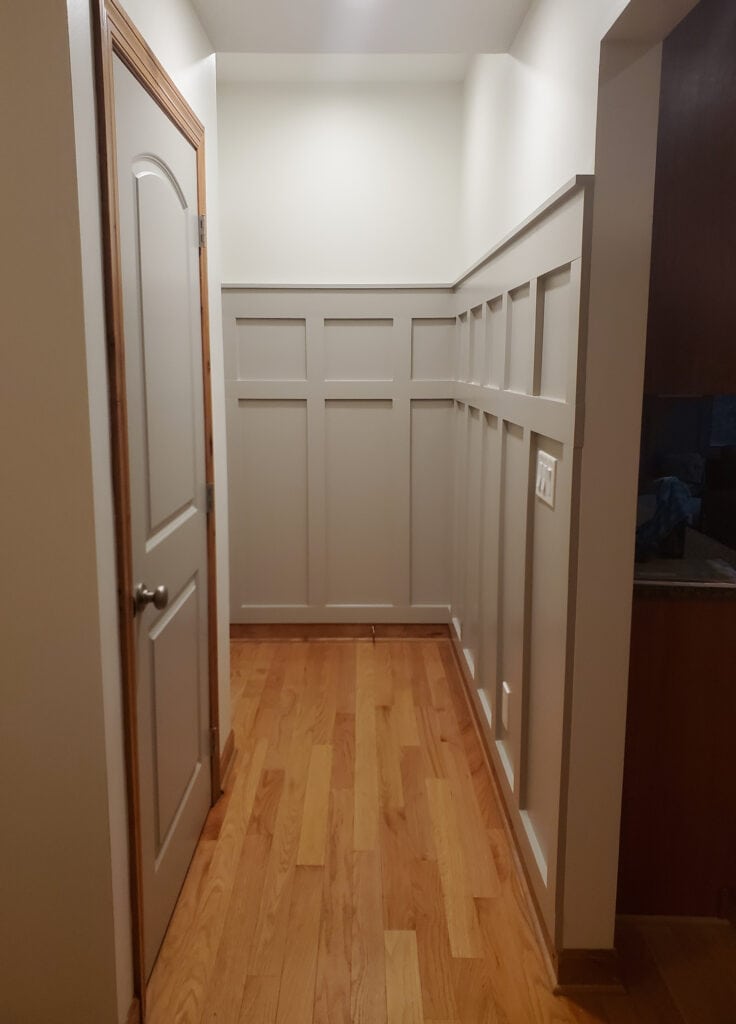 Hallway with board and batten painted Sherwin Williams Intellectual Gray, Alabaster walls, wood trim and oak wood flooring