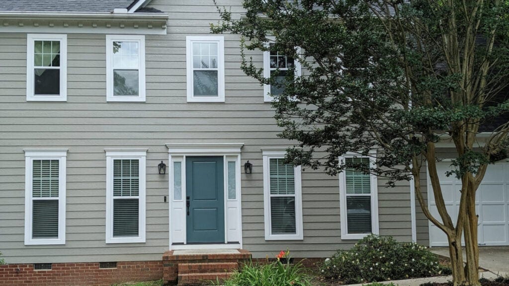 Sherwin Williams Intellectural Gray on exterior siding with red brick and a teal front door