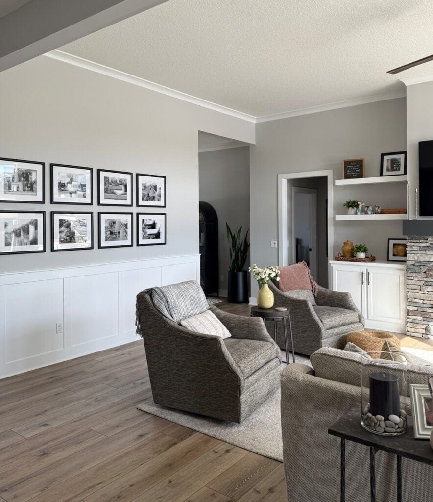 Sherwin Williams On the Rock in living room, with stone fireplace, white board and batten, wood flooring and neutral chairs (1)
