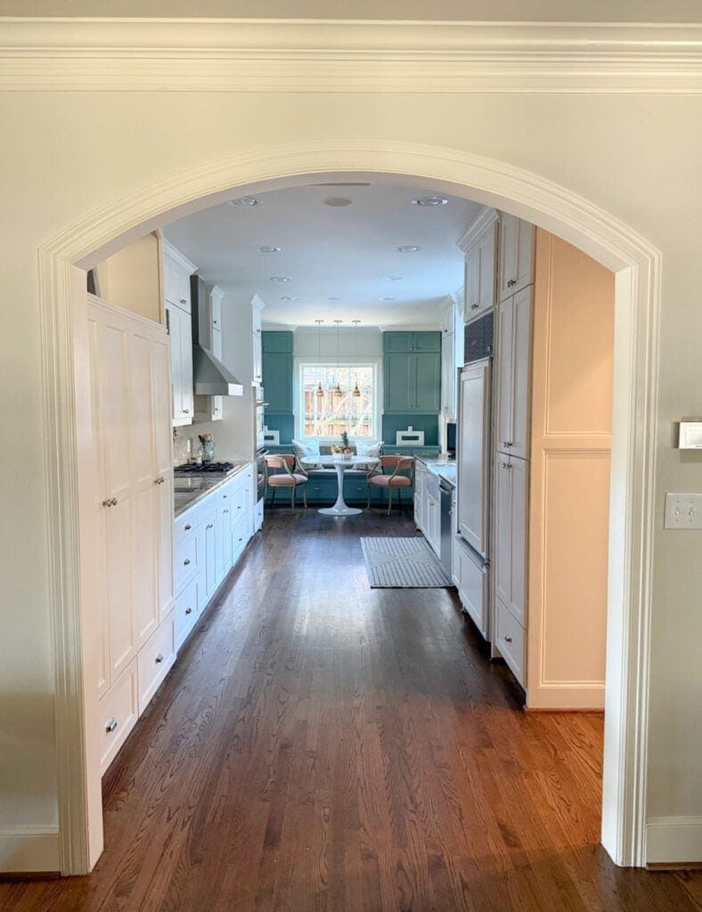 Sherwin Williams Underseas painted accent cabinets in galley kitchen with Dover White cream cabinets, wood flooring