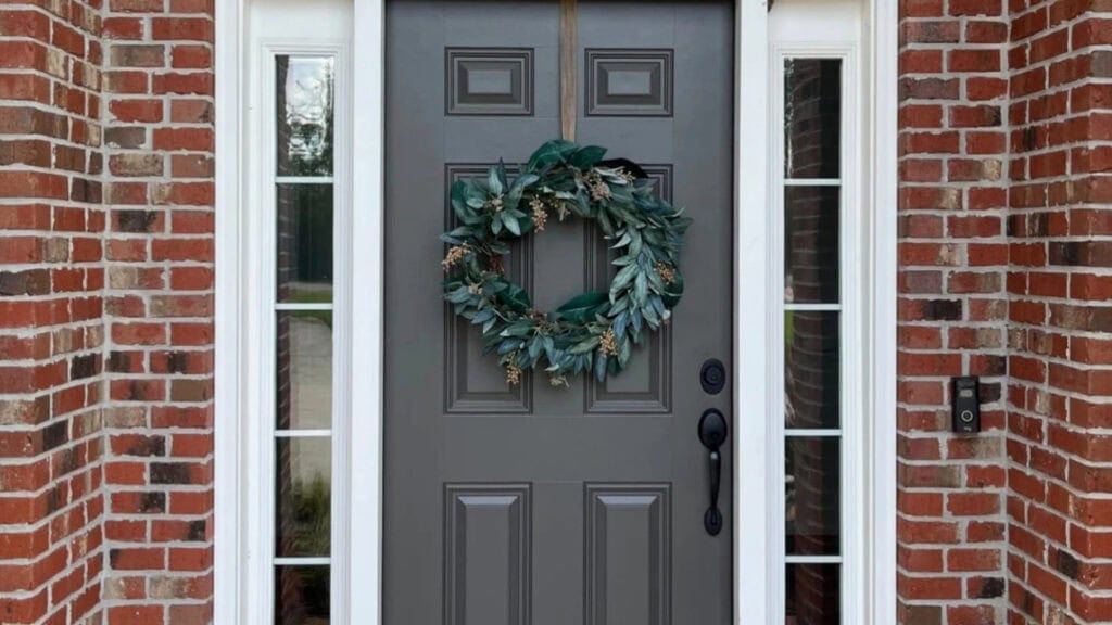 brick exterior, red brick with black, dark greige paint color on the front door on low natural lighting