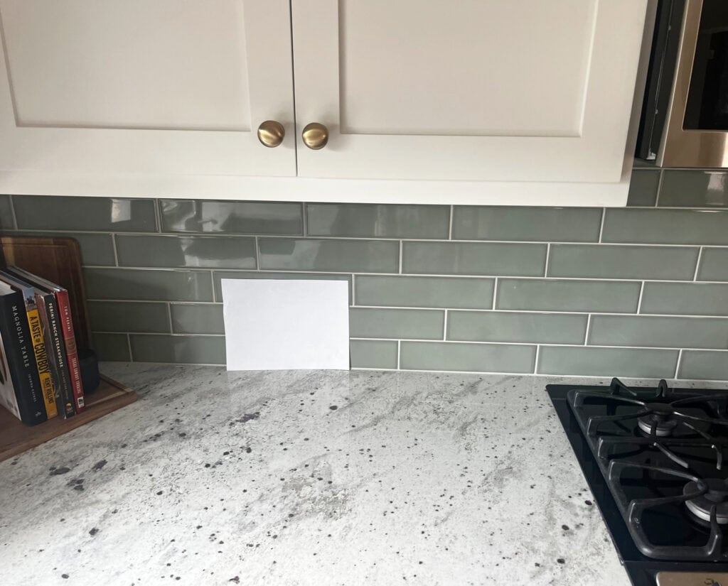 Andromeda White granite countertops, sage green-gray subway tile backsplash, Sherwin soft white cabinets
