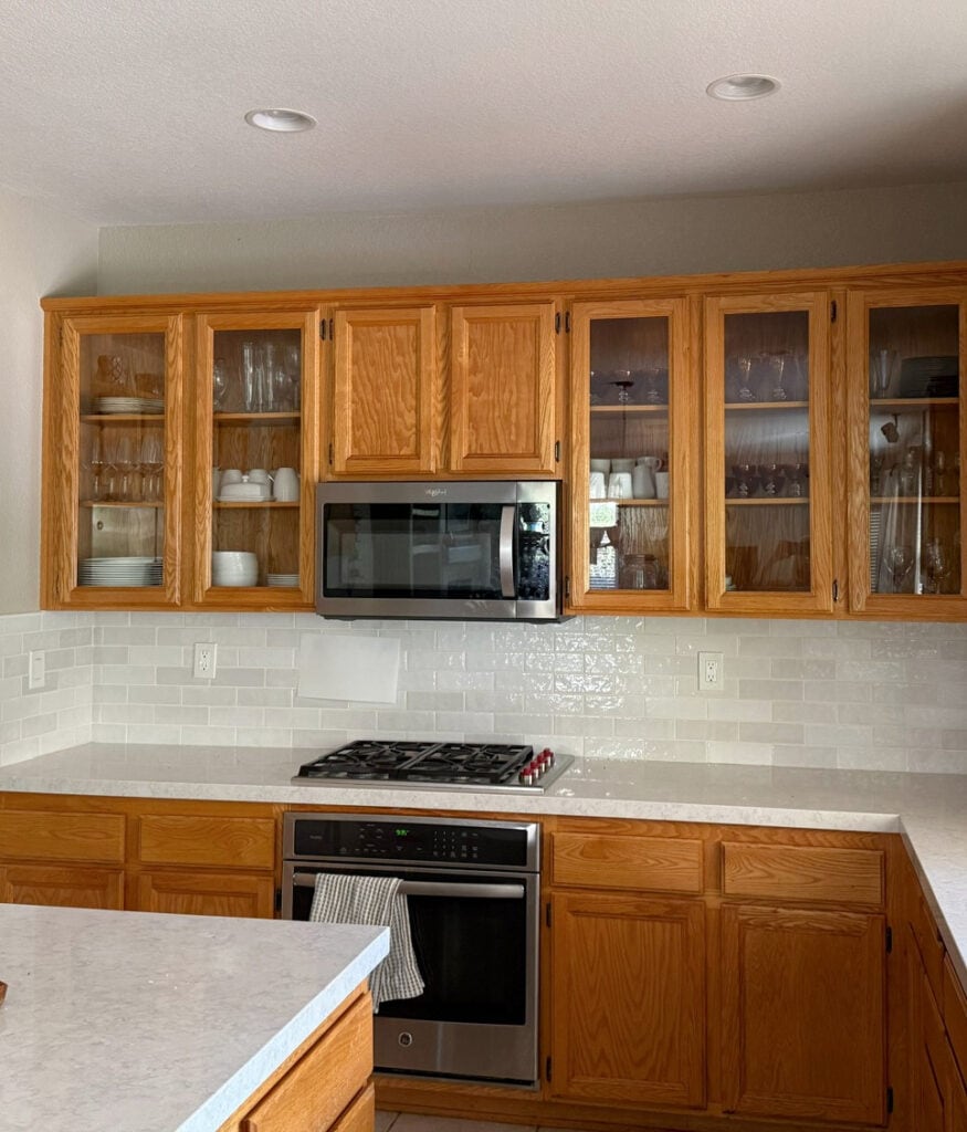 Golden orange stained oak wood cabinets in a kitchen with bedrosian cloe backsplash tile in subway