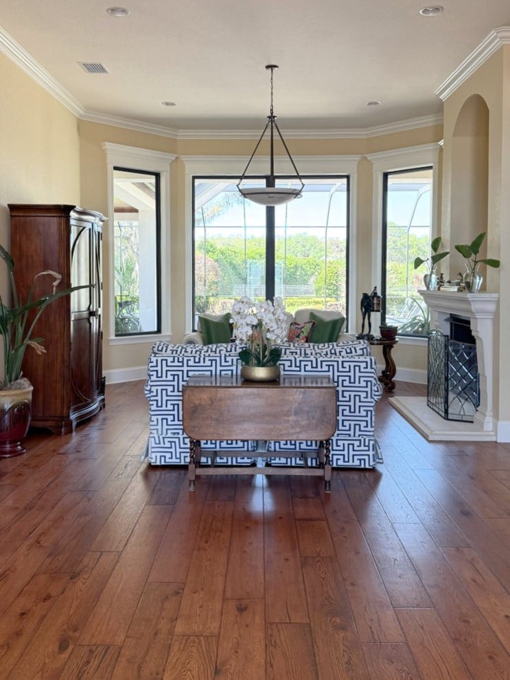 Wood flooring in family room with Sherwin Williams Ivoire, cream walls and Dover White trim, blue accent sofa in a pattern (1)